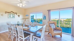 A dining area with a wooden table, white chairs, a telescope, and a view of the sea through large windows. - OCEAN FRONT, Pets OK, Ping Pong, Near Town and Discovery Trail (Ocean View A) (Long Beach)