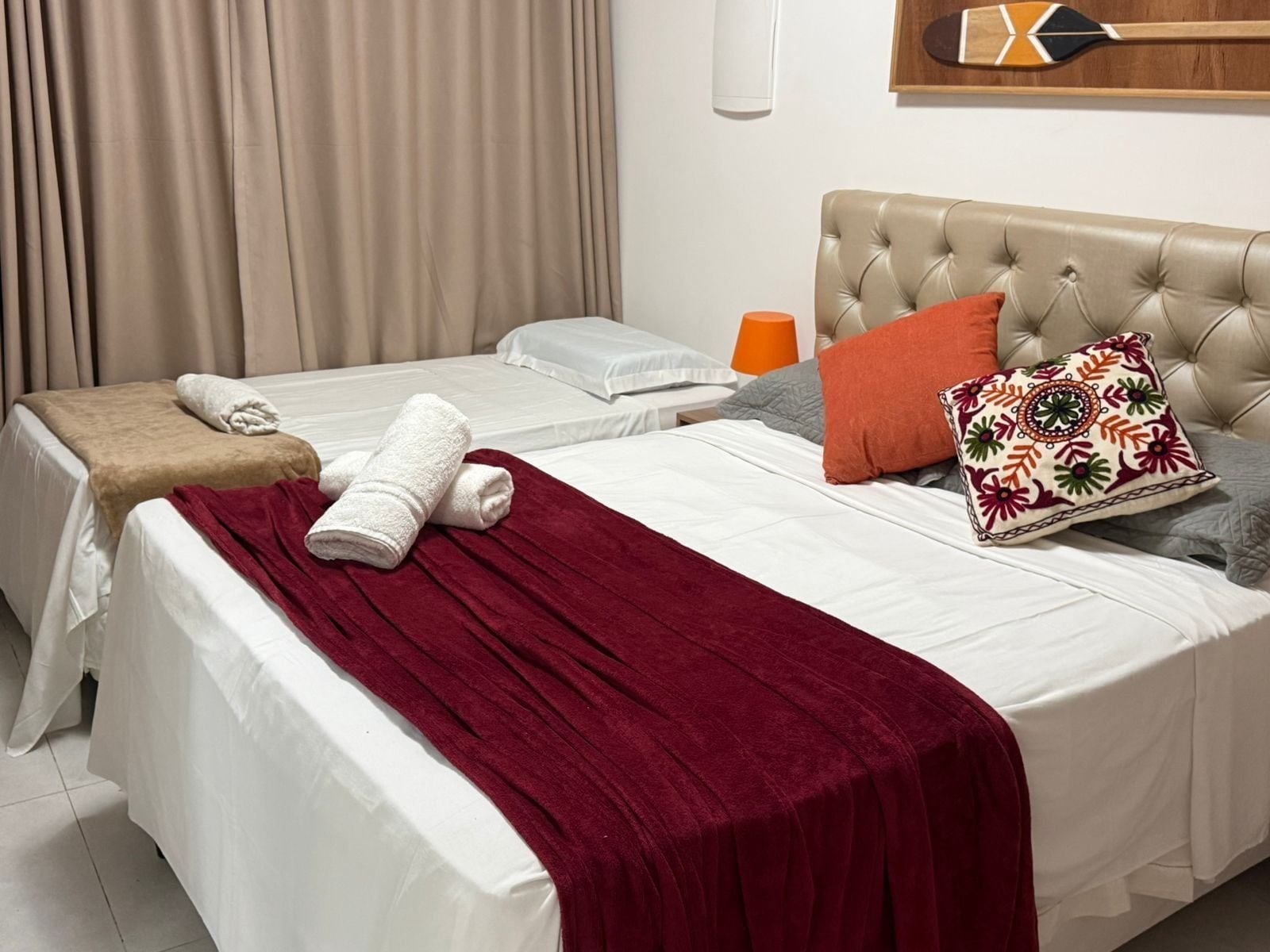 Una cama doble con una manta roja, dos almohadas y un cabecero de madera.