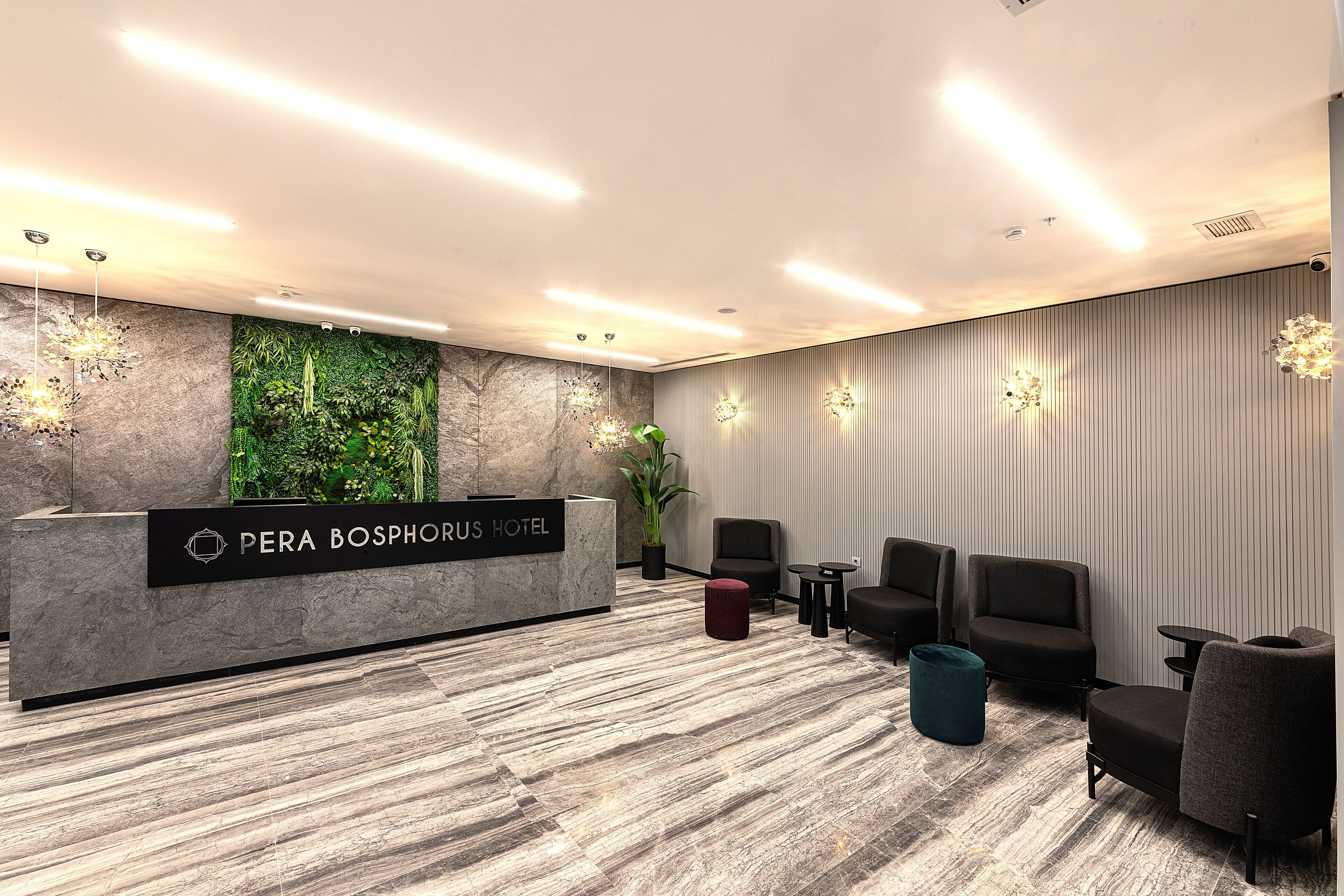 A hotel reception area with a marble reception desk, green wall decor, and seating for guests.