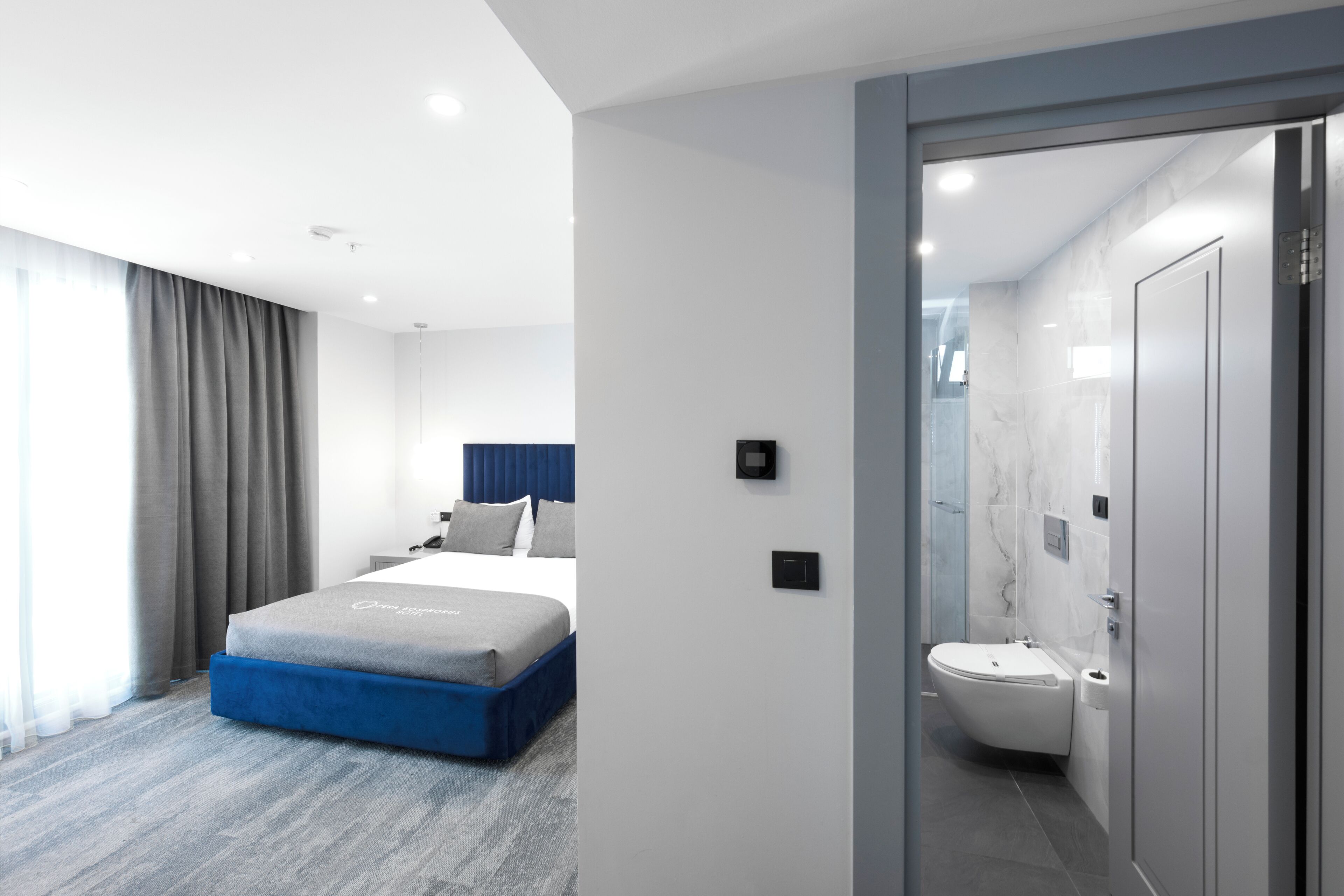 Una camera d'albergo moderna con un letto, un bagno e vista sulla città.