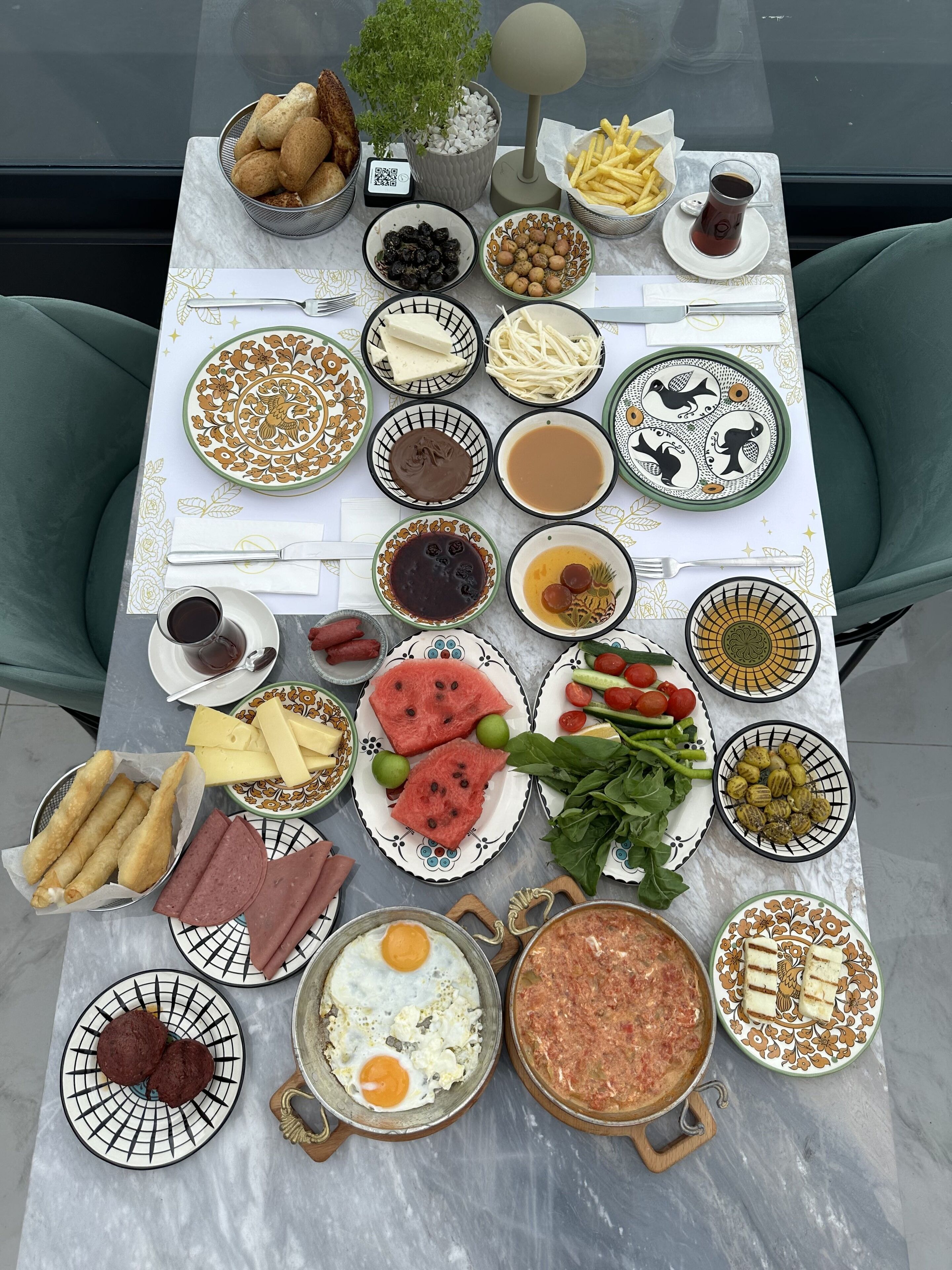 A table with various dishes including bread, eggs, and salads, suggesting a breakfast setting.