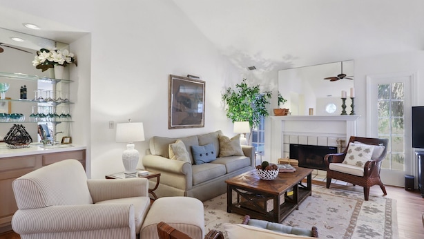 A living room with a sofa, armchairs, a coffee table, a fireplace, and a TV.