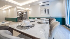 A modern dining area with a marble table set for four, surrounded by chairs. There is a kitchen area in the background with bar stools. - Mabaat - Al Yasmeen - 353 (Riyadh)