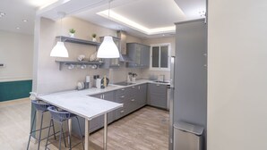 A modern kitchen with grey cabinets, a marble countertop, and pendant lighting. - Mabaat - Al Yasmeen - 353 (Riyadh)