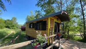 A wooden cabin with a yellow exterior, a covered porch, and potted plants. - Bohemian caravan (Chassenard)