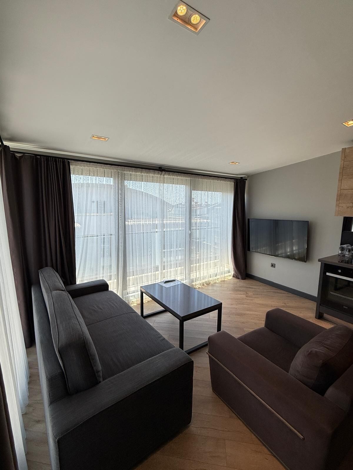 A modern living room with a sofa, a coffee table, and a flat-screen TV.