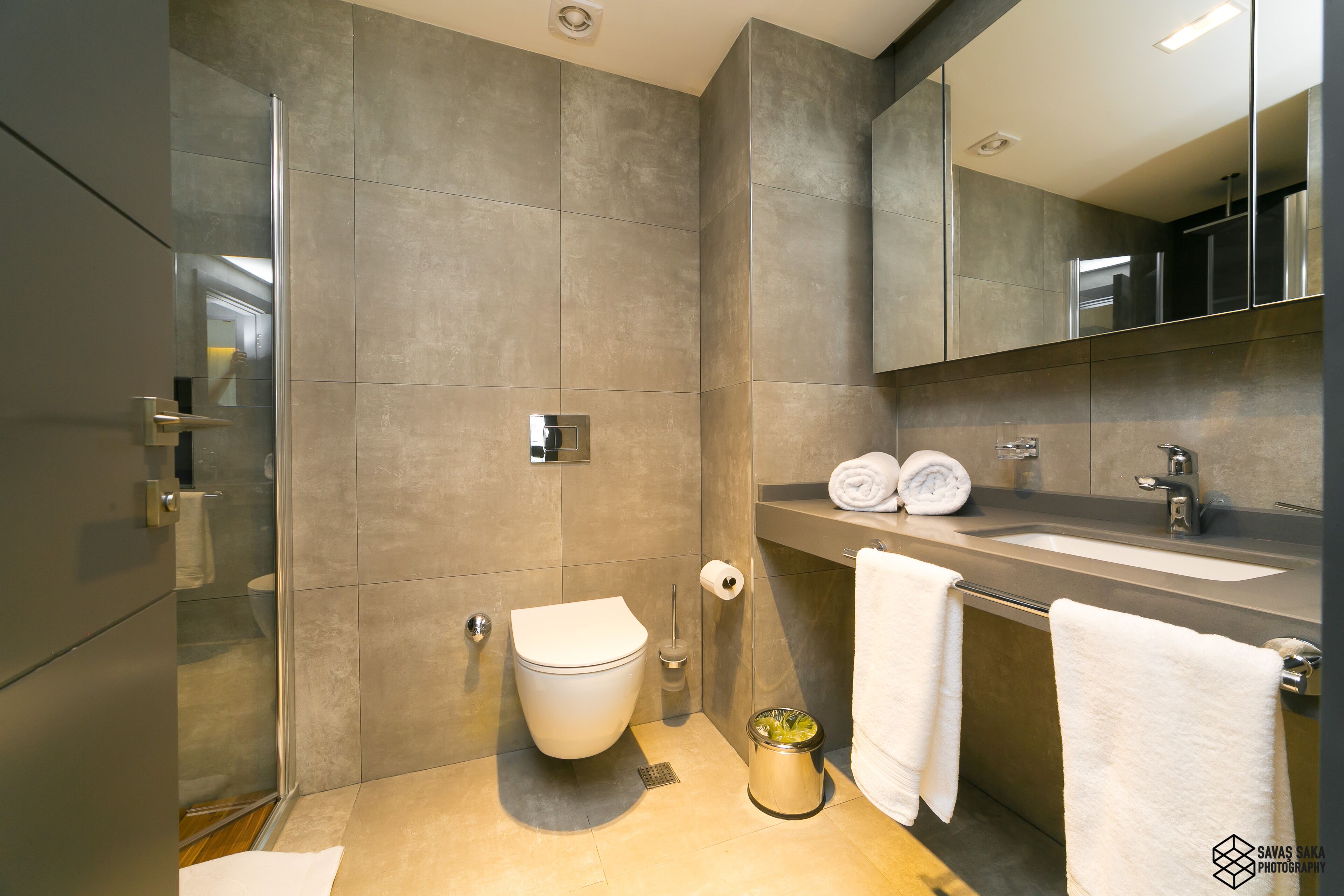 A modern bathroom with a toilet, sink, and mirror.