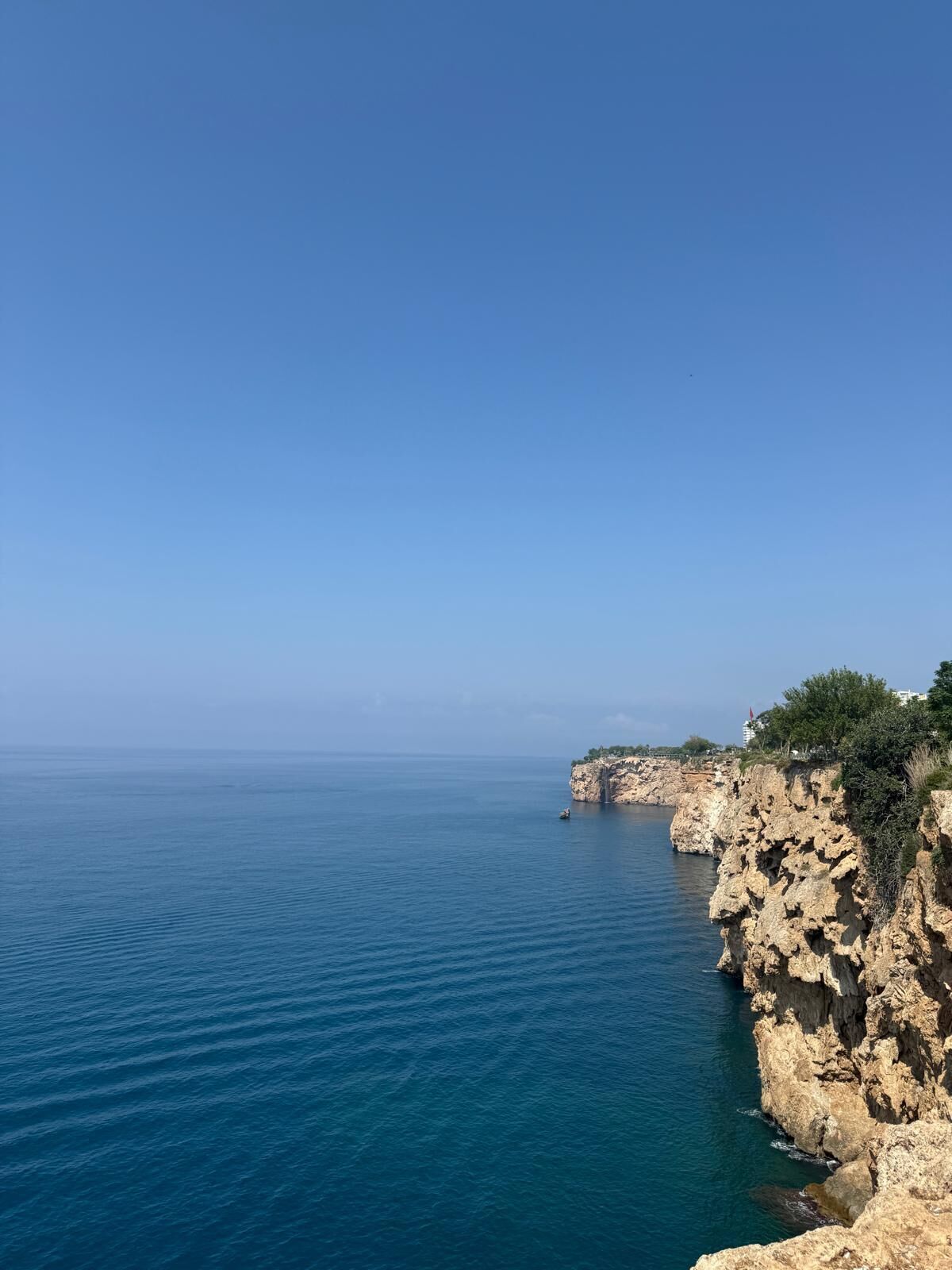 Paesaggio costiero con scogliere rocciose e mare calmo.