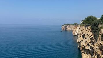 Paesaggio costiero con scogliere rocciose e mare calmo.
