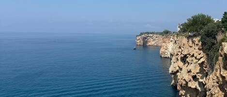 A coastal landscape with rocky cliffs and calm sea.