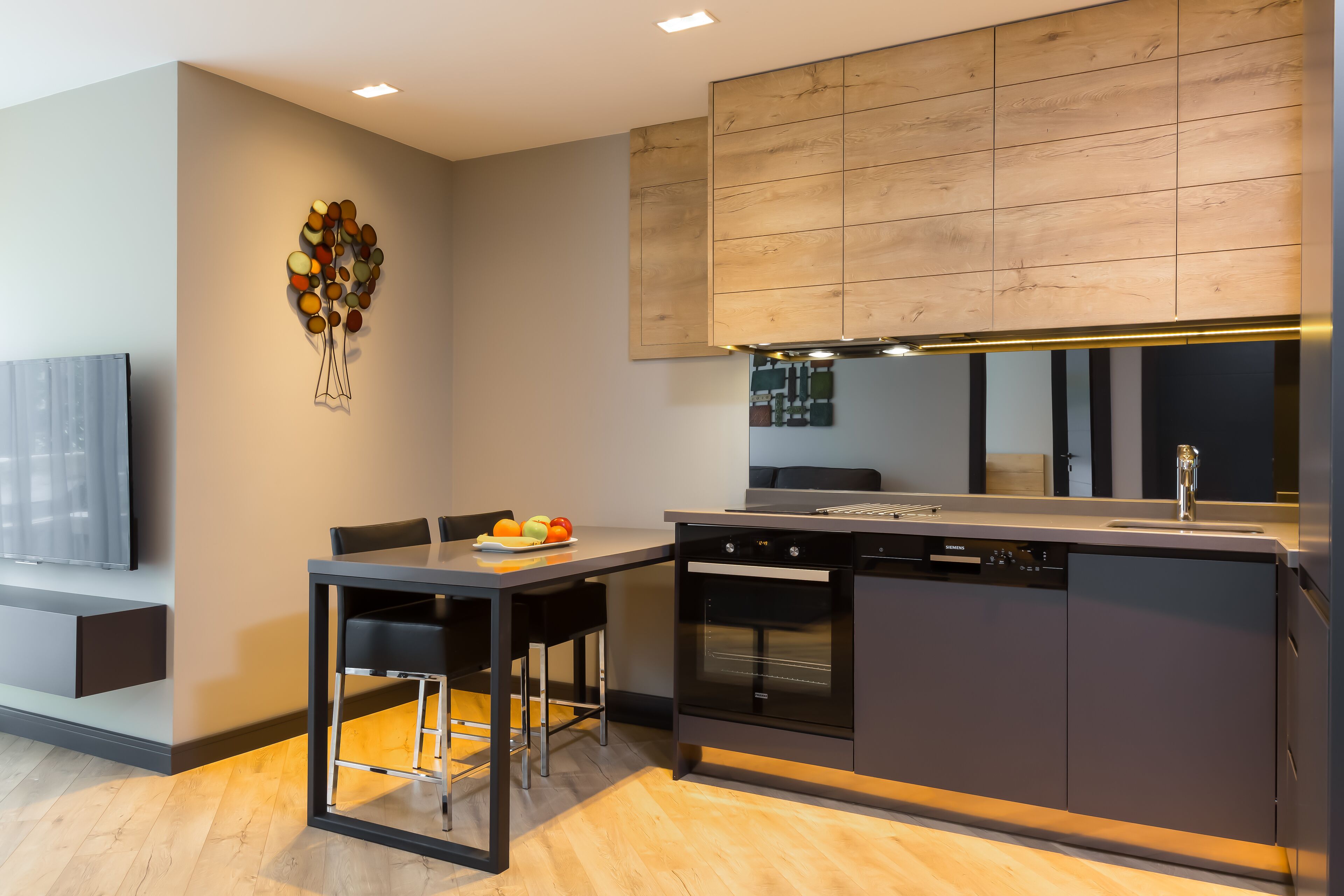 A modern kitchen with a built-in oven, dishwasher, and a large island with bar stools.