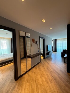 A modern living room with a large mirror, wooden flooring, and a sofa. - Z-Suites (Antalya)