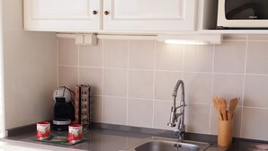Eine Küche mit weißen Schränken, einer Mikrowelle, einem Spülbecken und einer Kaffeemaschine.