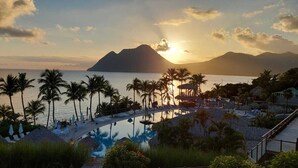 Un complexe hôtelier doté d’une piscine, de palmiers et offrant une vue sur le coucher de soleil.