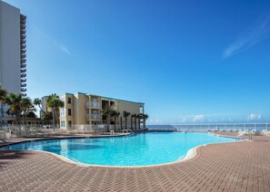 Relax by the resort pool surrounded by palm trees and a scenic view.