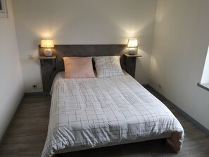 A neatly made bed with a geometric patterned bedspread, two bedside lamps, and a dark headboard.