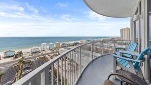 Un balcon avec vue sur la plage et l’océan, agrémenté d’une balustrade et de quelques chaises.