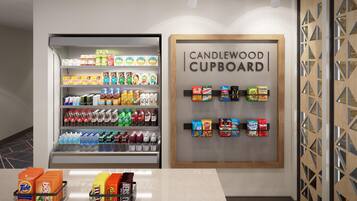 A beverage refrigerator stocked with various drinks and a wooden cupboard with snacks.