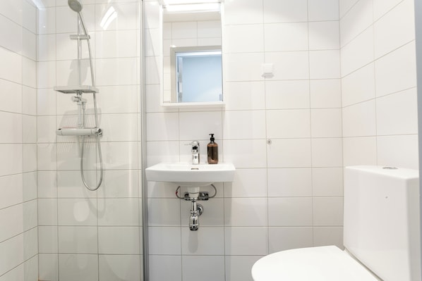 Un baño moderno con ducha, lavamanos e inodoro.