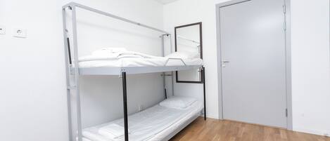 A bunk bed in a room with a wooden floor and a closed door.