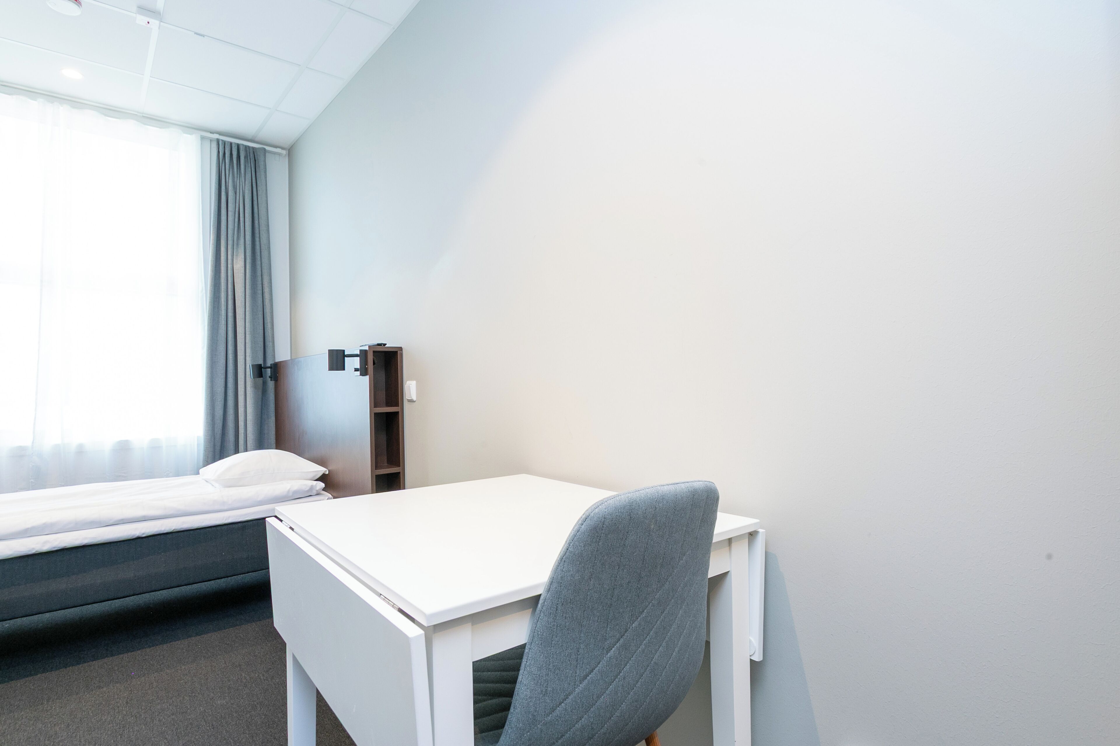 Una habitación de hotel con una cama, un escritorio y una silla.