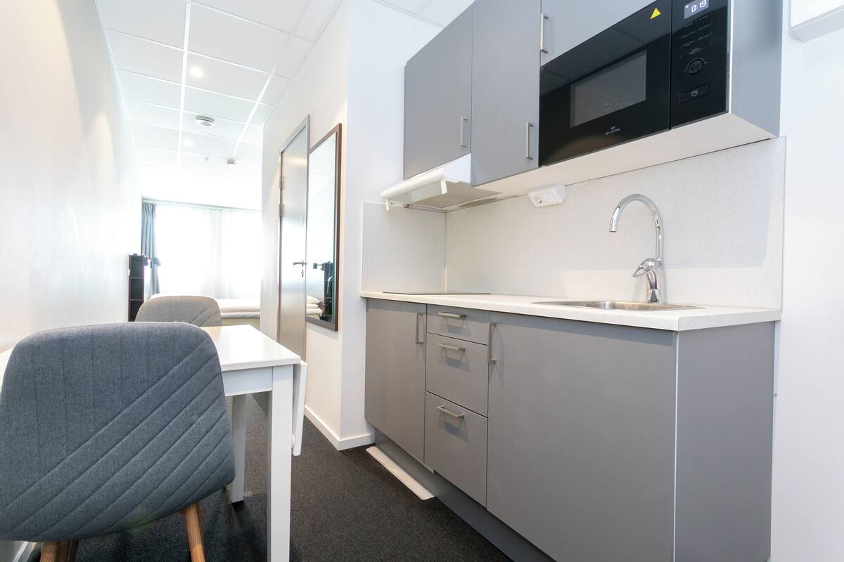 A modern kitchen with grey cabinets, a microwave, and a sink.