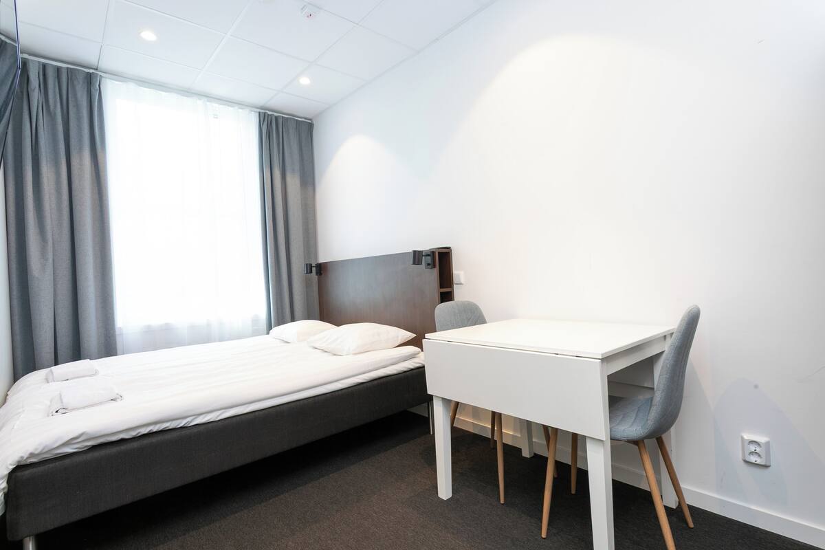 A hotel room with a bed, a desk, and a chair.