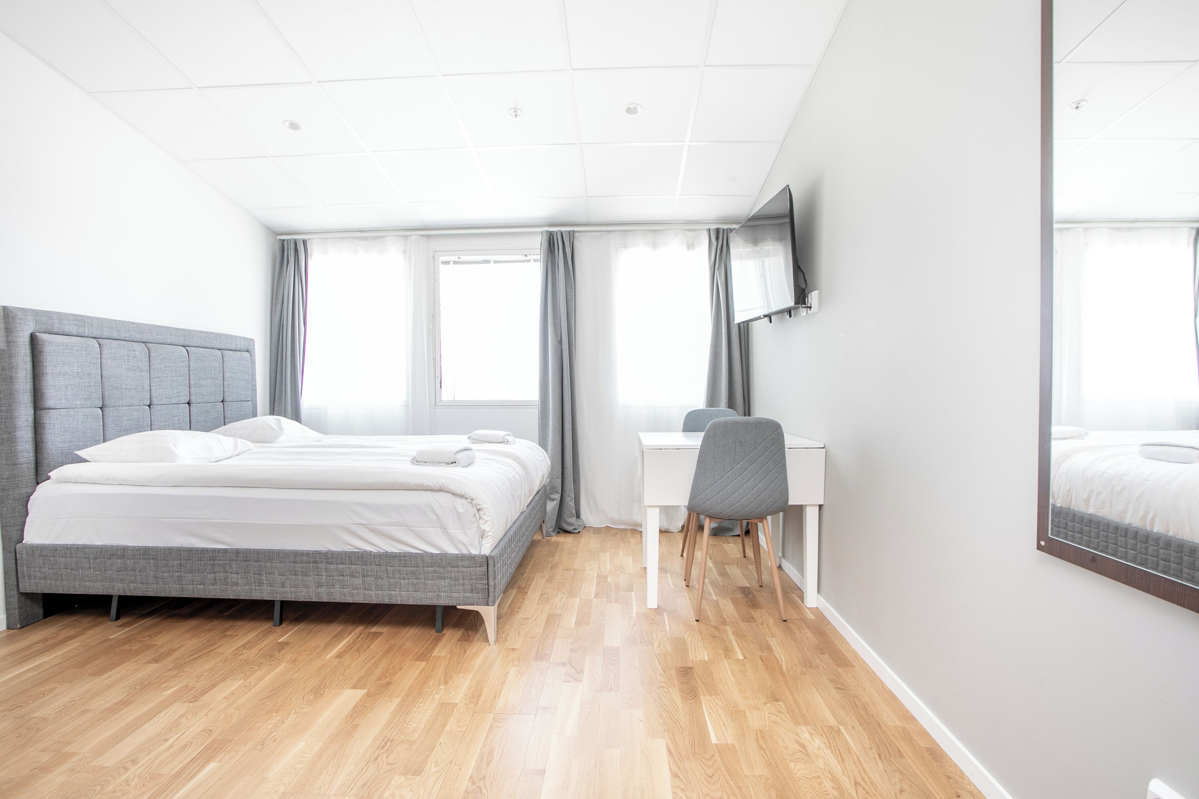 Quarto de hotel moderno com cama, escrivaninha e cadeira.