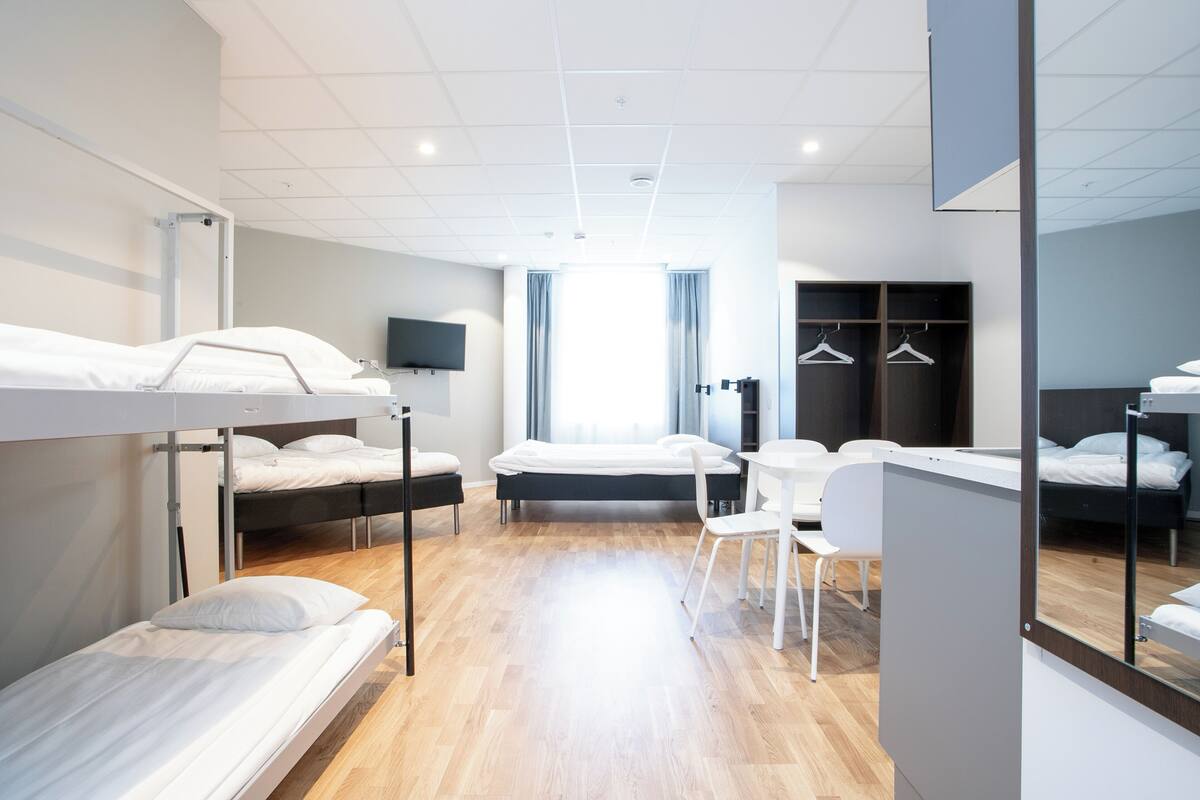 A modern hotel room with bunk beds, a desk, and a chair.