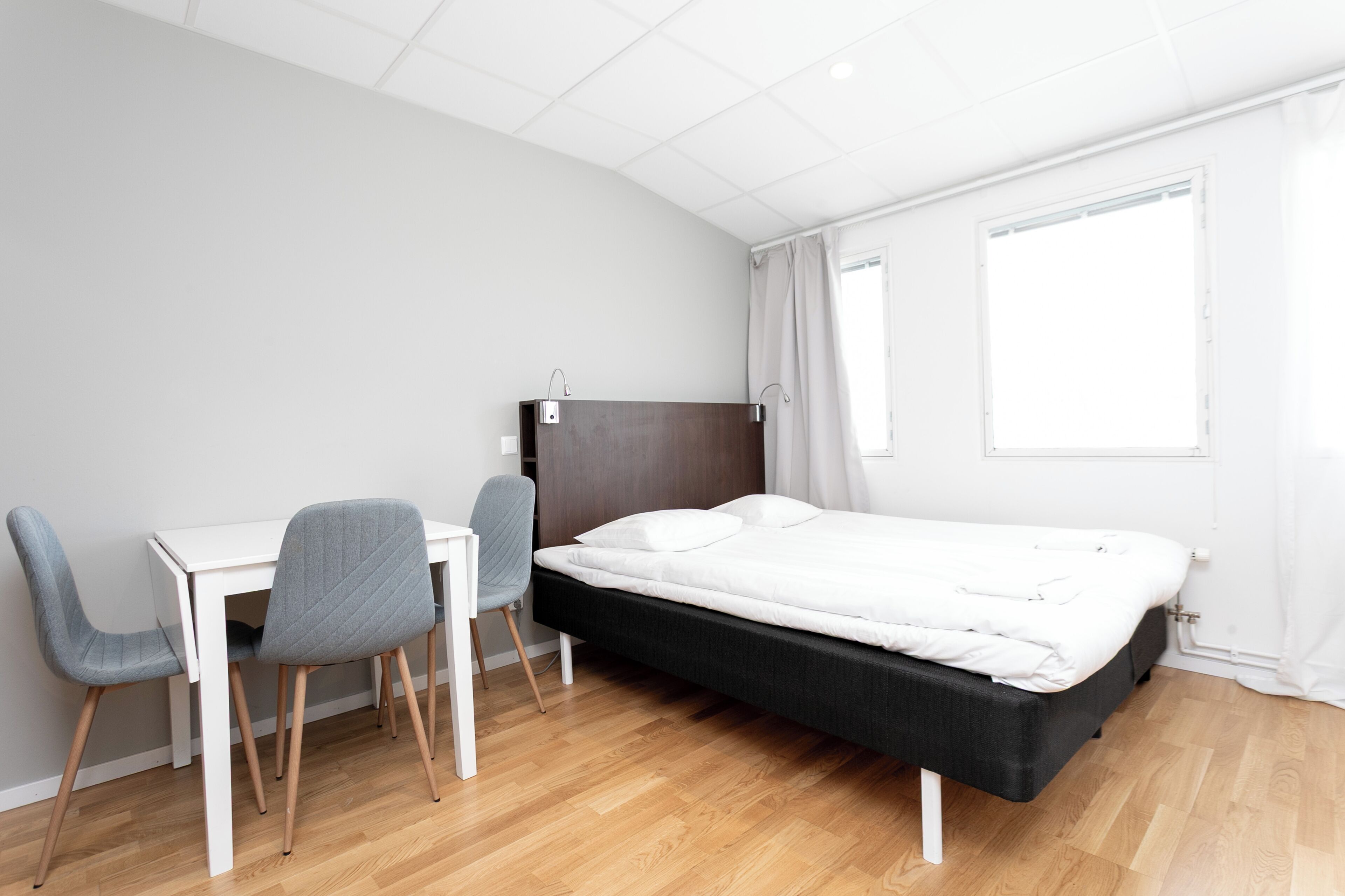 Un dormitorio moderno con cama, escritorio y dos sillas.