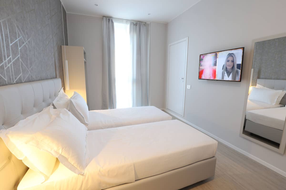 A modern hotel room with a large bed, a television, and a wardrobe.