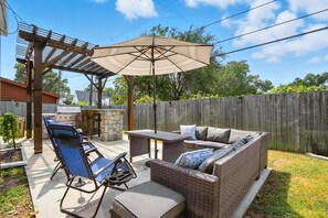 Una terrazza esterna con una pergola, un tavolo e un divano.