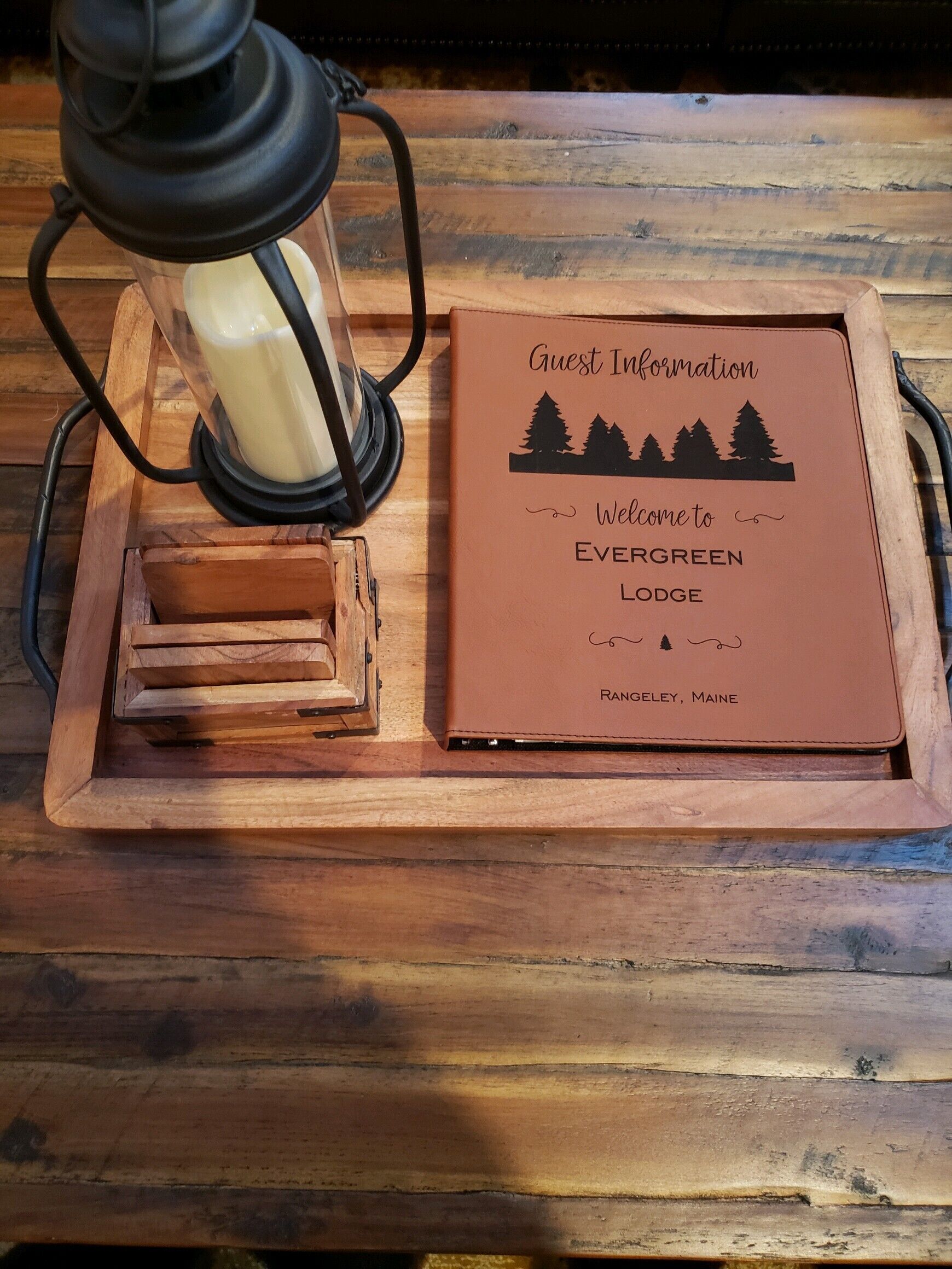 A wooden tray with a candle and a 'Guest Information' sign for Evergreen Lodge.