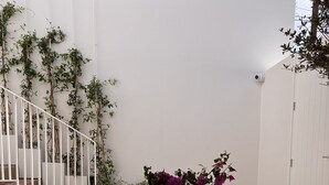 A dining area with a table set for a meal, surrounded by potted plants and a staircase. - Ethos Vegan Suites (Santorini)