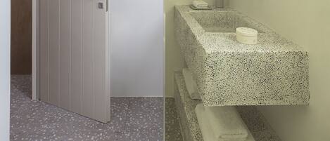 A bathroom with a white door, a towel hanging on the wall, a sink with a mirror, and a speckled floor.