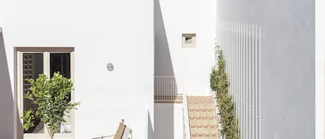 Un edificio bianco con un piccolo patio, una sedia e un vaso di fiori.