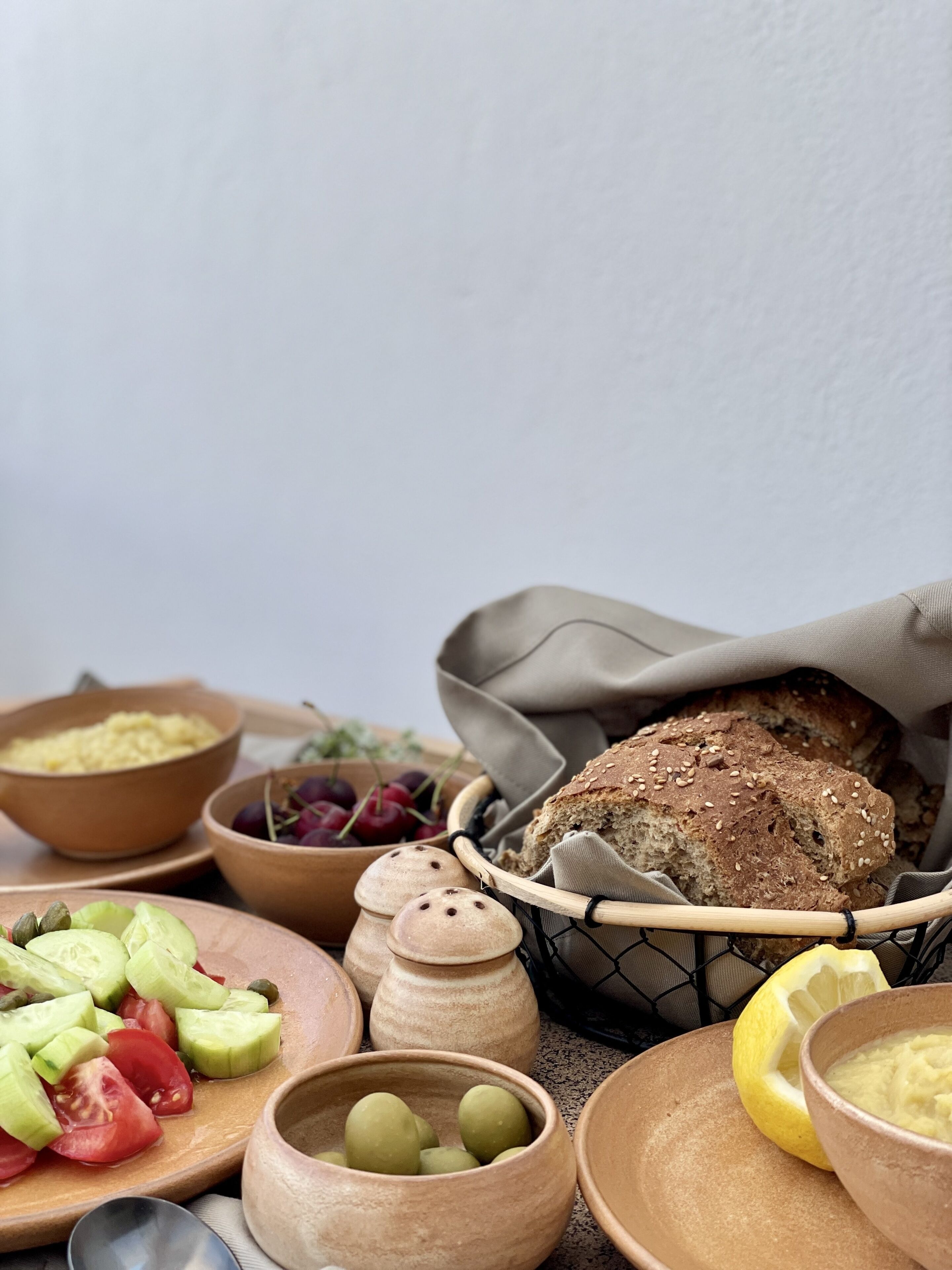 A rustic setting with a loaf of bread, bowls of food, and a basket.