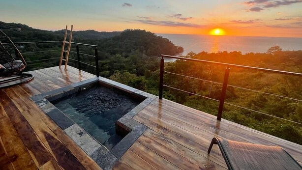 A wooden deck with a hot tub and a view of the sunset over the ocean. - Villa Asteria @ Mangata (Quepos)