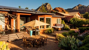 Ein Wohnhaus mit Terrasse, Gartenmöbeln, Grill und Bergblick.