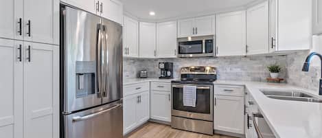 Enjoy cooking in this well-equipped kitchen with a refrigerator, microwave, oven, sink, and countertop area.