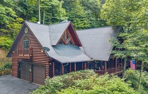A log cabin with a steeply pitched roof, a large garage, and a porch with a railing. - 4BR / 4 1/2 BA,  Covered deck with Hot-tub overlooking the mountains (Maggie Valley)