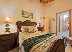 A bedroom with a wooden headboard, a bed with patterned bedding, two bedside tables with lamps, and a painting on the wall. - 4BR / 4 1/2 BA,  Covered deck with Hot-tub overlooking the mountains (Maggie Valley)