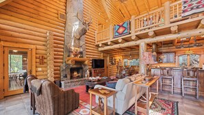 A log cabin interior with a fireplace, wooden furniture, and a dining area. - 4BR / 4 1/2 BA,  Covered deck with Hot-tub overlooking the mountains (Maggie Valley)
