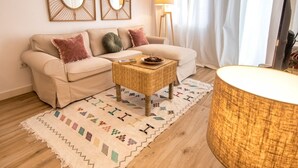 A living room with a beige sofa, two throw pillows, a woven coffee table, a patterned rug, and a lamp. - SibsSanlucar- Maritimo-1ª beach line- cozy- terrace (Sanlúcar de Barrameda)