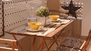 A wooden table with a metal frame, set with yellow bowls, clear glasses, and a small potted plant. - SibsSanlucar- Maritimo-1ª beach line- cozy- terrace (Sanlúcar de Barrameda)