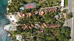 An aerial view of a resort with multiple bungalow-style buildings, a tennis court, and a swimming pool. - ON THE CARIBBEAN SEA - CRYSTAL APARTMENT (Boca Chica)