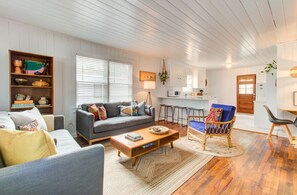 Relax in this spacious living area with a sofa, coffee table, and wicker chair, perfect for unwinding.