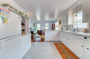 Kitchen area with refrigerator, microwave, sink, and chair, offering a convenient space for meal preparation.