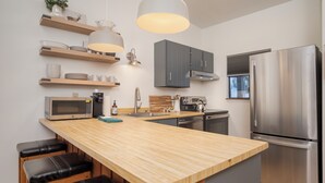 A modern kitchen with wooden countertops, a stainless steel refrigerator, and built-in cabinets. - Beaver Village Unit #0332 Remodeled 1 Bedroom vaulted ceiling & private deck (Winter Park)