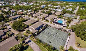 Vue aérienne d’un quartier résidentiel avec des maisons, un court de tennis et une piscine.